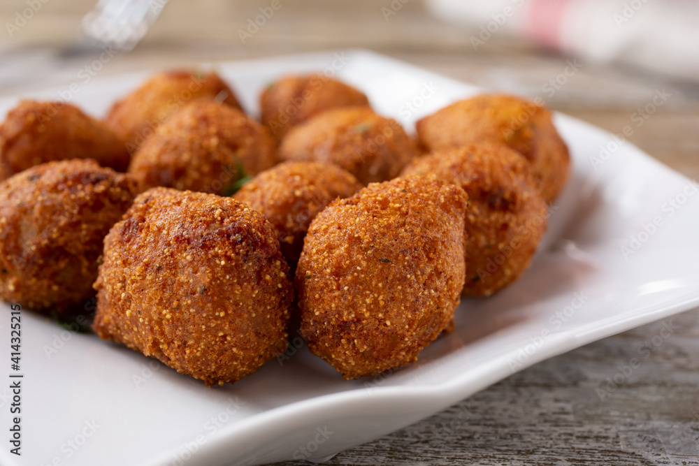 A closeup view of a plate of deep fried hush puppies. A closeup view of a plate of deep fried hush puppies.