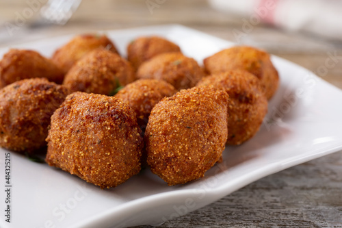 A closeup view of a plate of deep fried hush puppies.