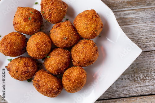 Фотография A top down view of a plate of deep fried hush puppies.