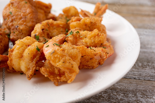 A closeup view of a plate of deep fried shrimp and fish.