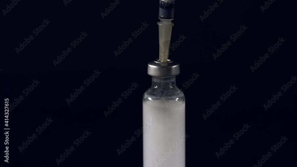 Filling up a syringe with a white substance from a small bottle. Close up shot, isolated background. Filling up a syringe with a white substance from a small bottle. Close up shot, isolated background.