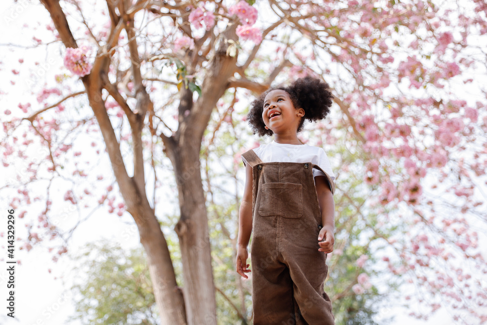 A cute Afro girls under flowering tree in park. A cute Afro girls under flowering tree in park.