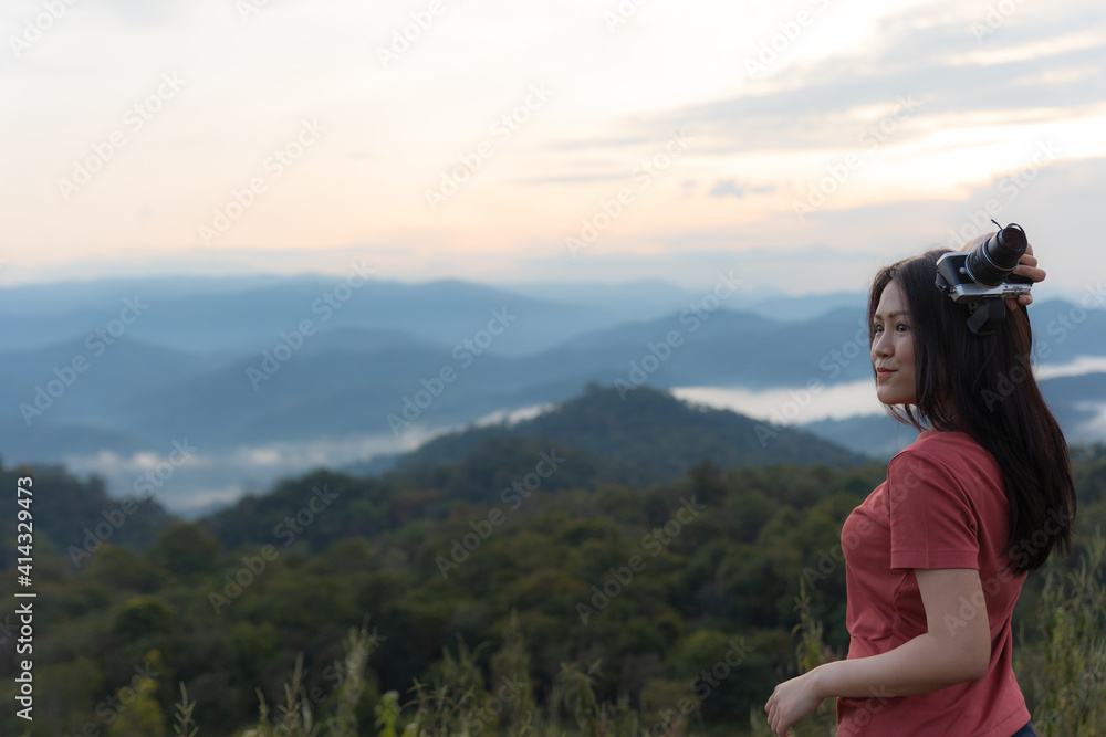Happy Asian woman in red shirt traveler with camera at the view point for sunrise. Travel Lifestyle adventure concept