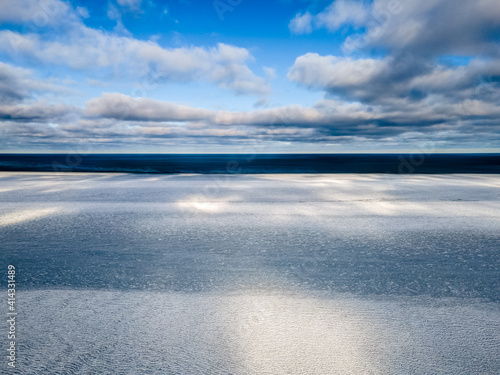 Blue water and ice. Sea in winter from drone in sunny cloudy day