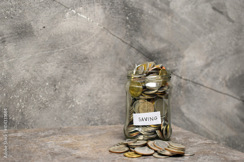 Coins in glass jar and a pile of coins on marble table. Money saving fanancial concept. photo