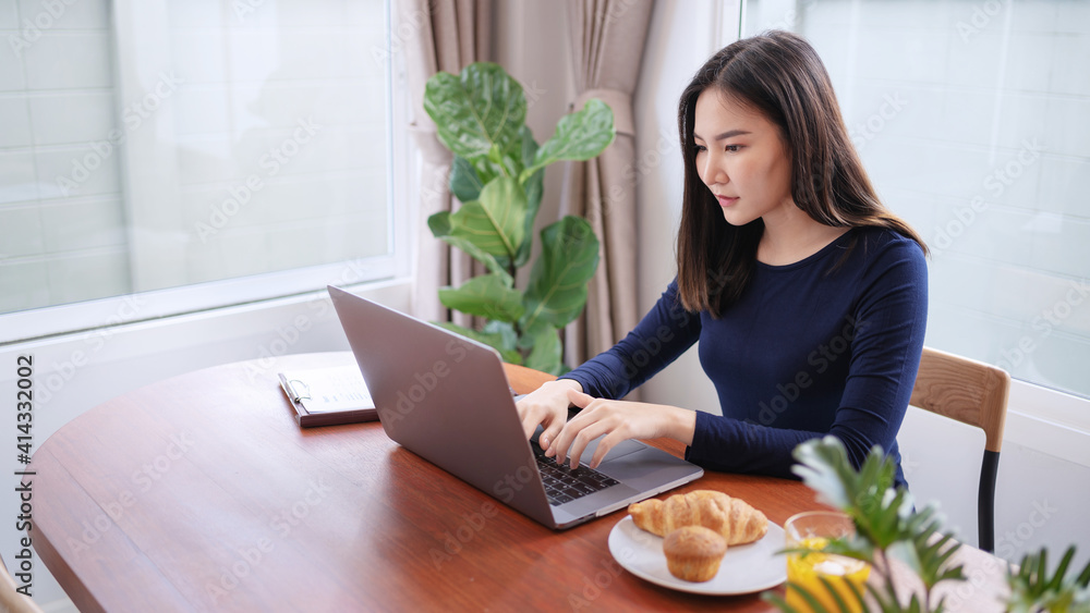 Fototapeta premium Busy asian woman eating lunch while working from home in covid-19 coronavirus quarantine..