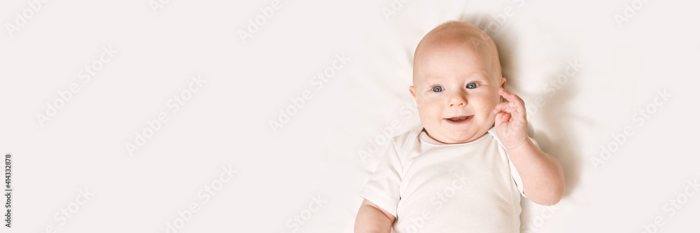 Cute small boy lying at bed. Childhood concept. Light background. Smiling child. Happy emotion. Copyspace. Stay home. Mockup. Horizontal banner. White clothes Cute small boy lying at bed. Childhood concept. Light background. Smiling child. Happy emotion. Copyspace. Stay home. Mockup. Horizontal banner. White clothes