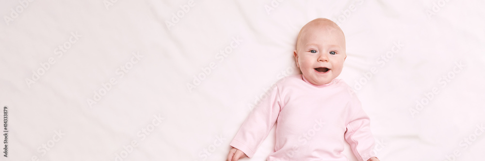 Cute small boy lying at bed. Childhood concept. Light background. Smiling child. Happy emotion. Copyspace. Stay home. Mockup. Horizontal banner