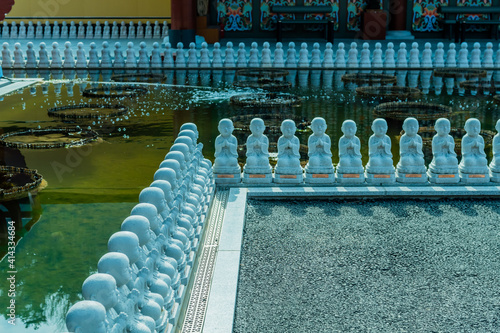Small statues of praying Buddha line man made pond at Manbulsa Temple in Yeongcheon, South Korea.