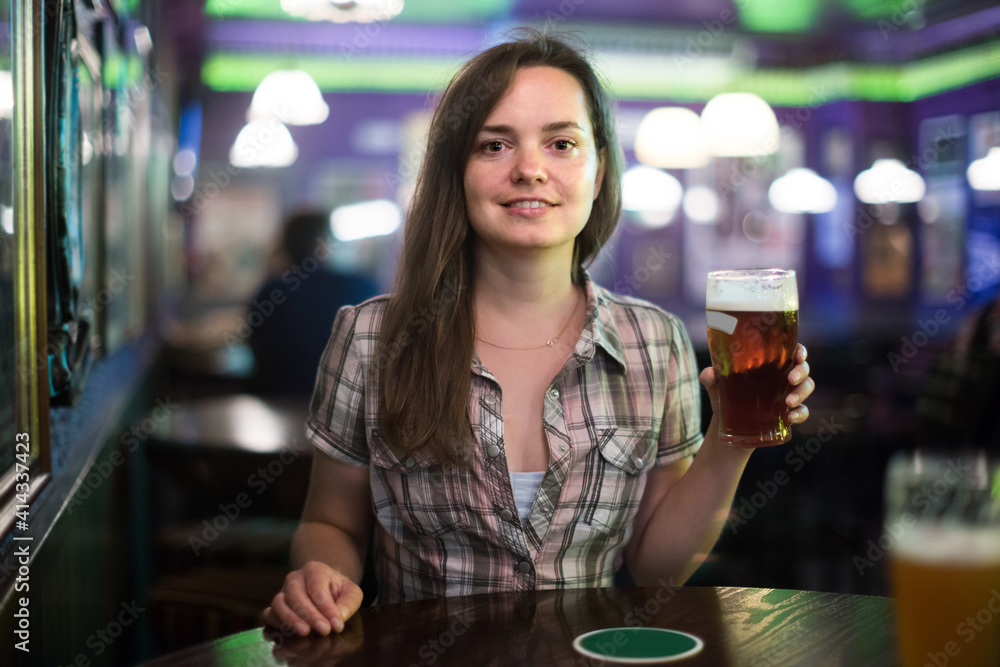 beautiful girl sits in bar with beer glass