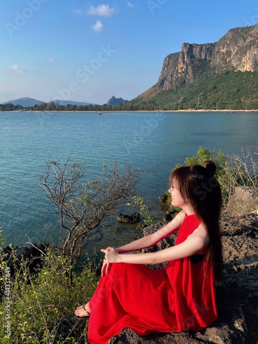 Asian women has long hair wearing red dress and sunglasses sit ride on the cliff in casual day