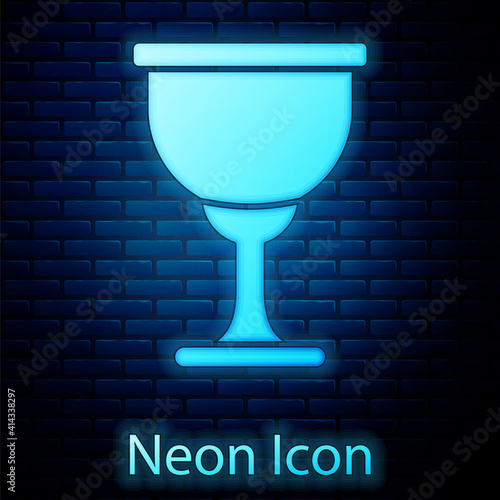 Glowing neon Holy grail or chalice icon isolated on brick wall background. Christian chalice. Christianity icon. Vector.