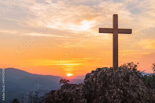 Silhouettes of crucifix symbol on top mountain with bright sunbeam on the colorful sky background