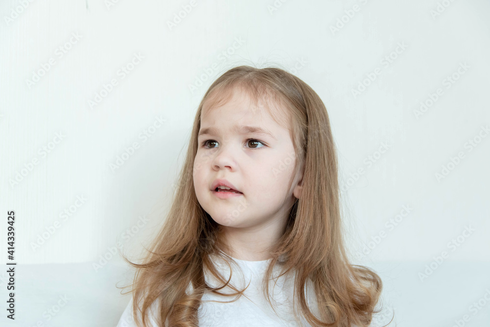 Portrait of a girl 3-5 years old with long blond hair in a white T-shirt. Portrait of a girl 3-5 years old with long blond hair in a white T-shirt.