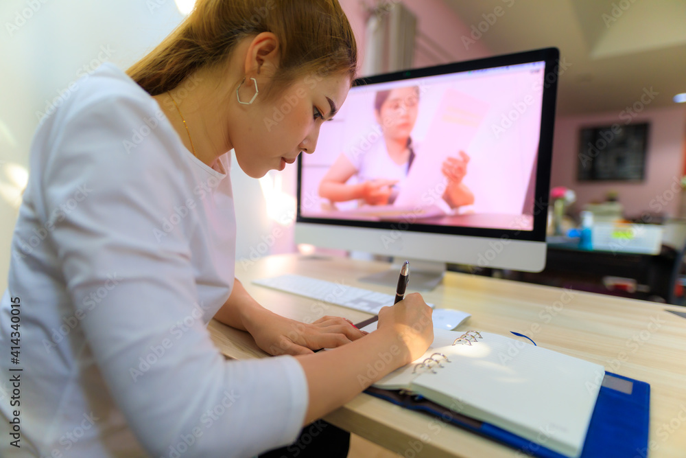 An Asian woman working from home by using teleconference for communication with her team.