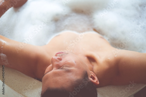 Asain man relaxing in the bathtub with foam bath. 