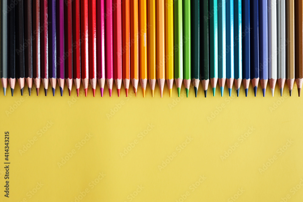 Line of colored pencils on yellow background top view. Rainbow palette wood pencils. Line of colored pencils on yellow background top view. Rainbow palette wood pencils.