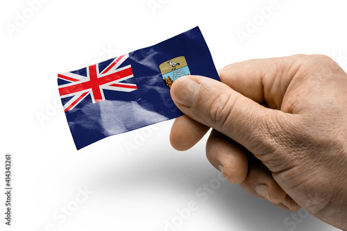 Hand holding a card with a national flag the Saint Helena