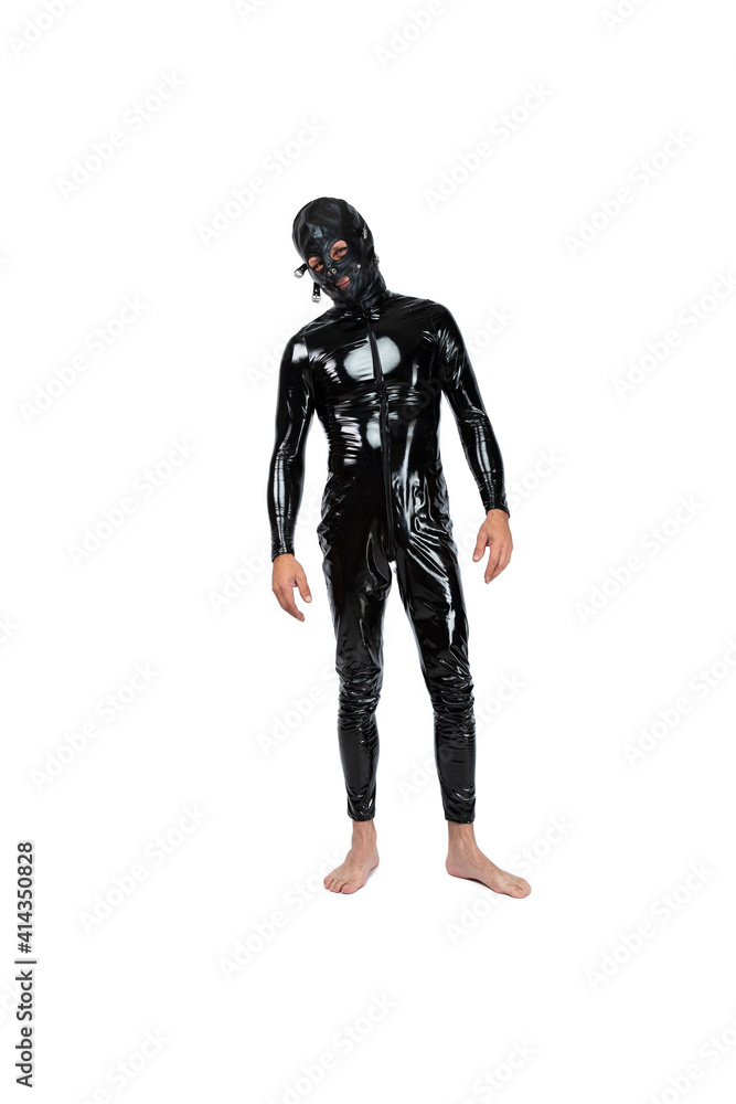 Foto Stock Man stands, dressed in latex fetish clothes and pvc mask. bdsm  costume for role-playing adult games. Man in the black catsuit on isolated  white background in Studio | Adobe Stock