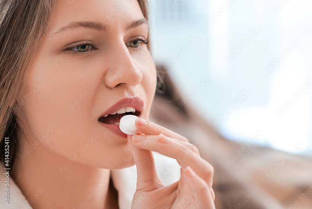 Beautiful young woman taking pills at home, closeup Beautiful young woman taking pills at home, closeup