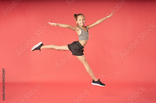Adorable girl gymnast jumping against gymnast