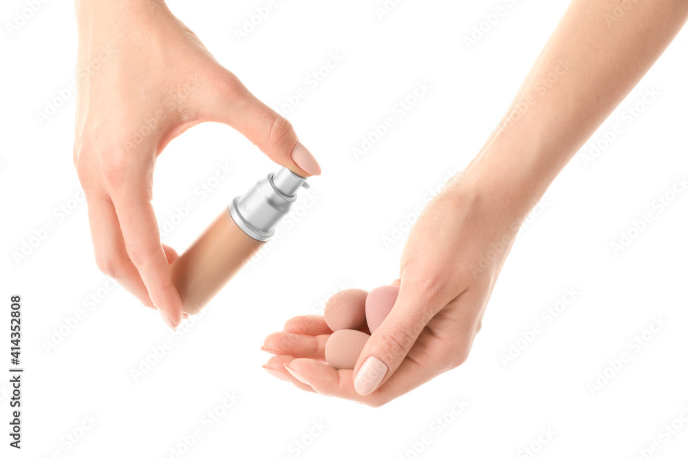 Hands with makeup sponges and concealer on white background