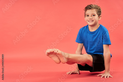 Cheerful boy doing exercise against red background
