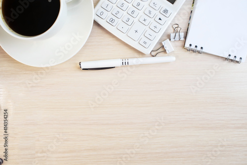 Office desk with calculator notepad coffee cup and pen on wooden desk. Flat space to copy the view from the top.