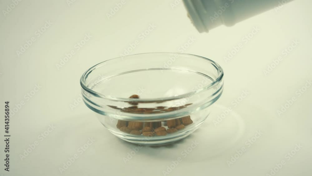 Close up video of pouring cat food in a bowl over white background. Close up video of pouring cat food in a bowl over white background.