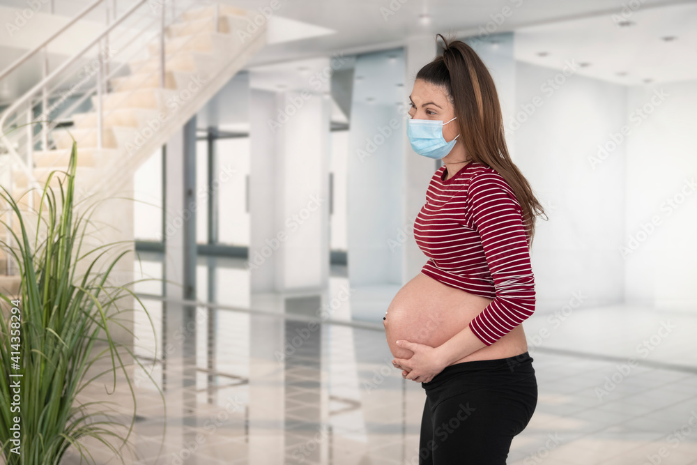 Pregnant woman standing while holding her belly