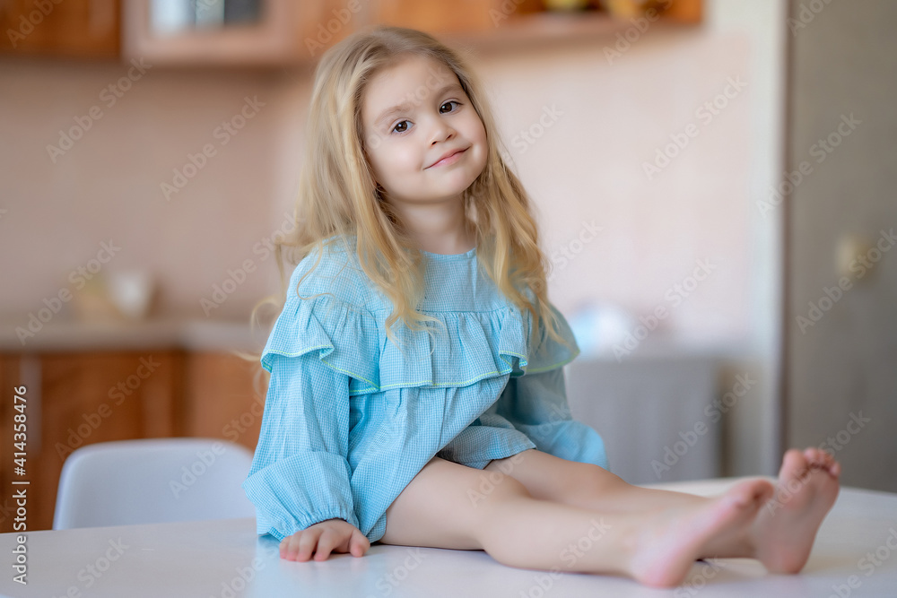cute little girl sitting in the kitchen looking at the camera cute little girl sitting in the kitchen looking at the camera
