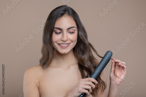Woman straightening curl of hair using iron