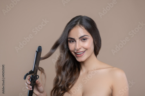 Woman holding strand of hair in curling iron