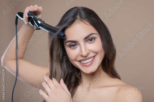 Woman doing hairstyle on beige background