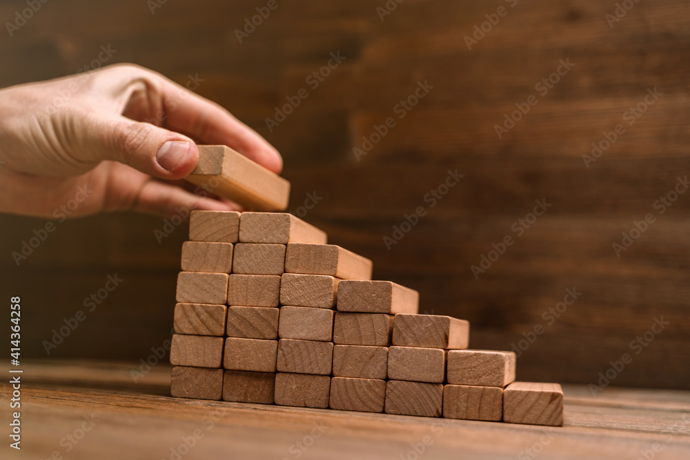 Business concept - hand builds a ladder from wooden blocks. Driving business at the peak concept. Business concept - hand builds a ladder from wooden blocks. Driving business at the peak concept.