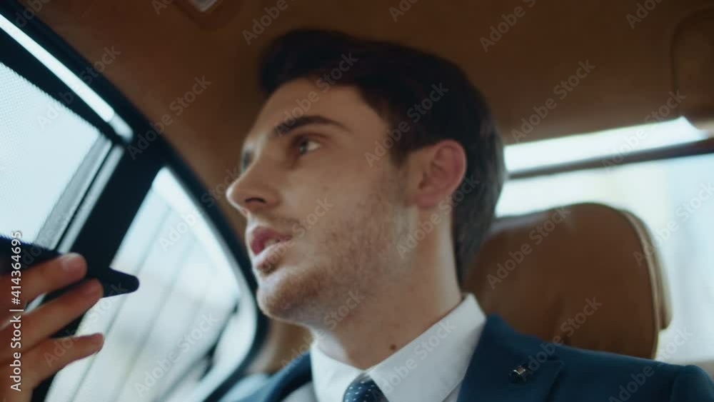Focused male professional recording voice message on smartphone in modern car. Focused male professional recording voice message on smartphone in modern car.