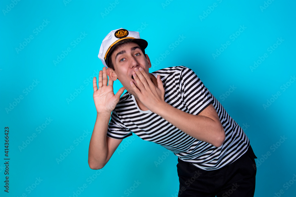Funny experienced sailor ready for marine travel. Cheerful young sailor. Expression of emotions. The guy is posing on a blue background. Funny experienced sailor ready for marine travel. Cheerful young sailor. Expression of emotions. The guy is posing on a blue background.