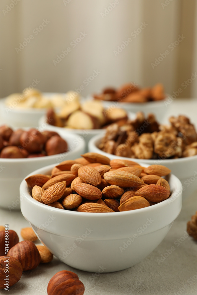 Bowls with different nuts on white textured background, space for text Bowls with different nuts on white textured background, space for text