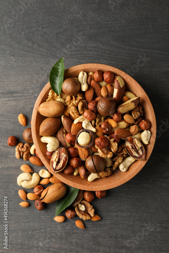 Wood bowl with different tasty nuts on gray wooden background