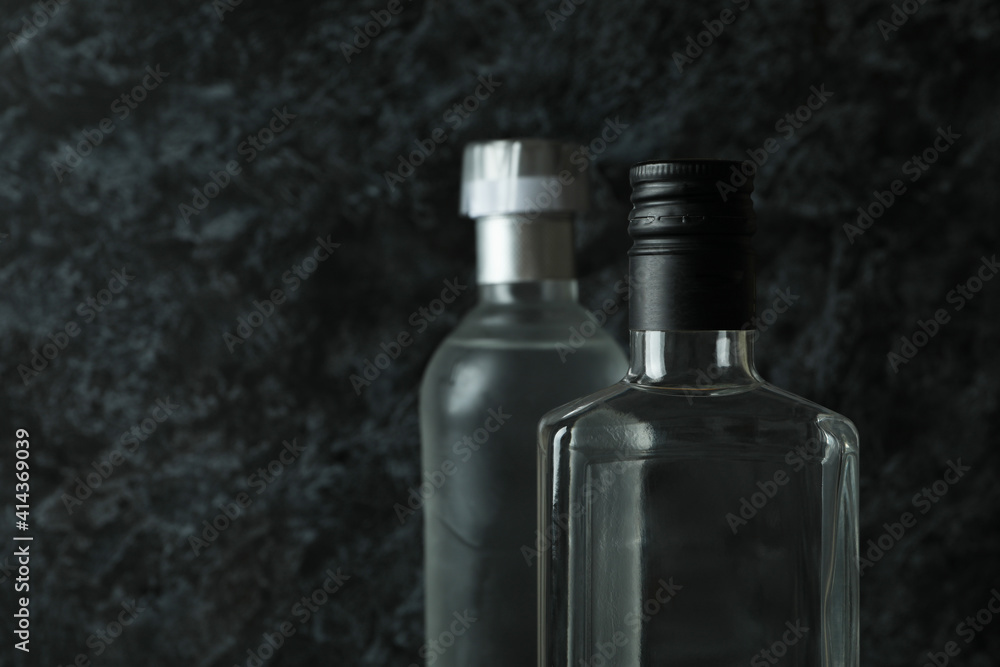 Blank bottles of vodka on black smokey background, space for text