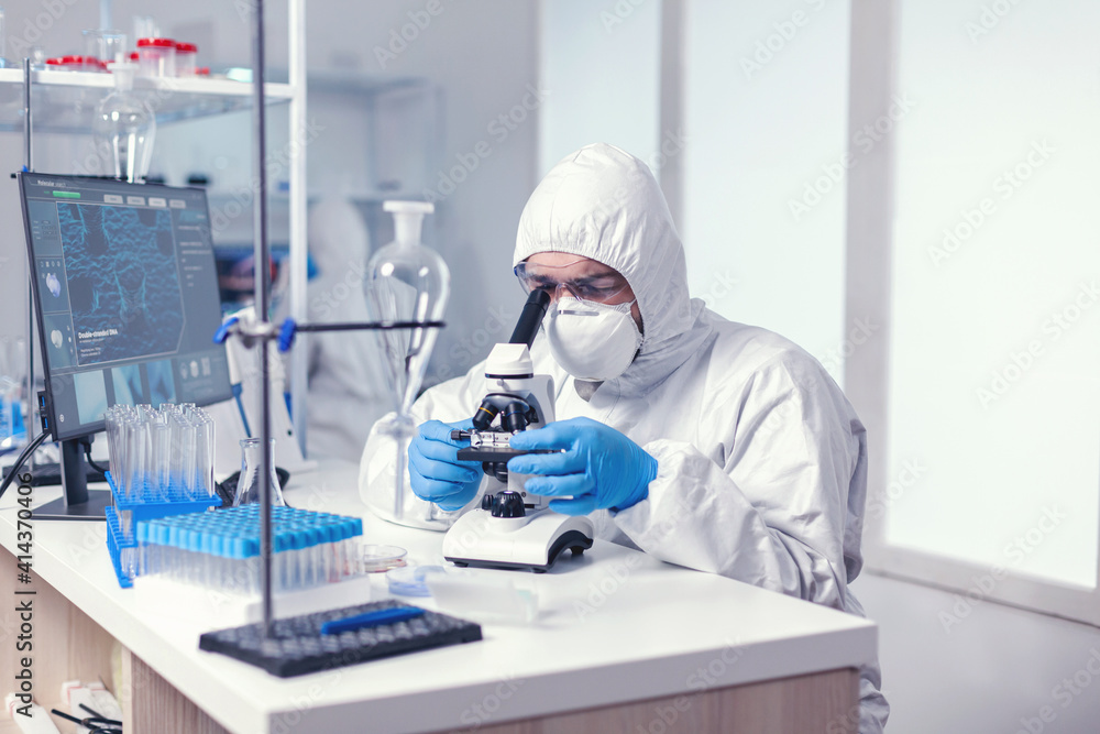 Biotechnology scientist in ppe suit researching cure for coronavirus using microscope in modern laboratory. Virolog in coverall during coronavirus outbreak conducting healthcare scientific analysis. Biotechnology scientist in ppe suit researching cure for coronavirus using microscope in modern laboratory. Virolog in coverall during coronavirus outbreak conducting healthcare scientific analysis.