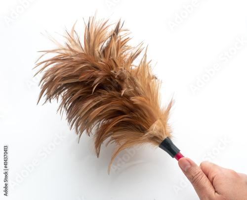 Hand was holding a feather duster on a white background, A feather duster is an implement used for cleaning, Housework. photo