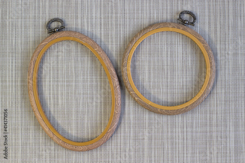 Embroidery hoop, oval and round frames on rough grey linen, top view close up