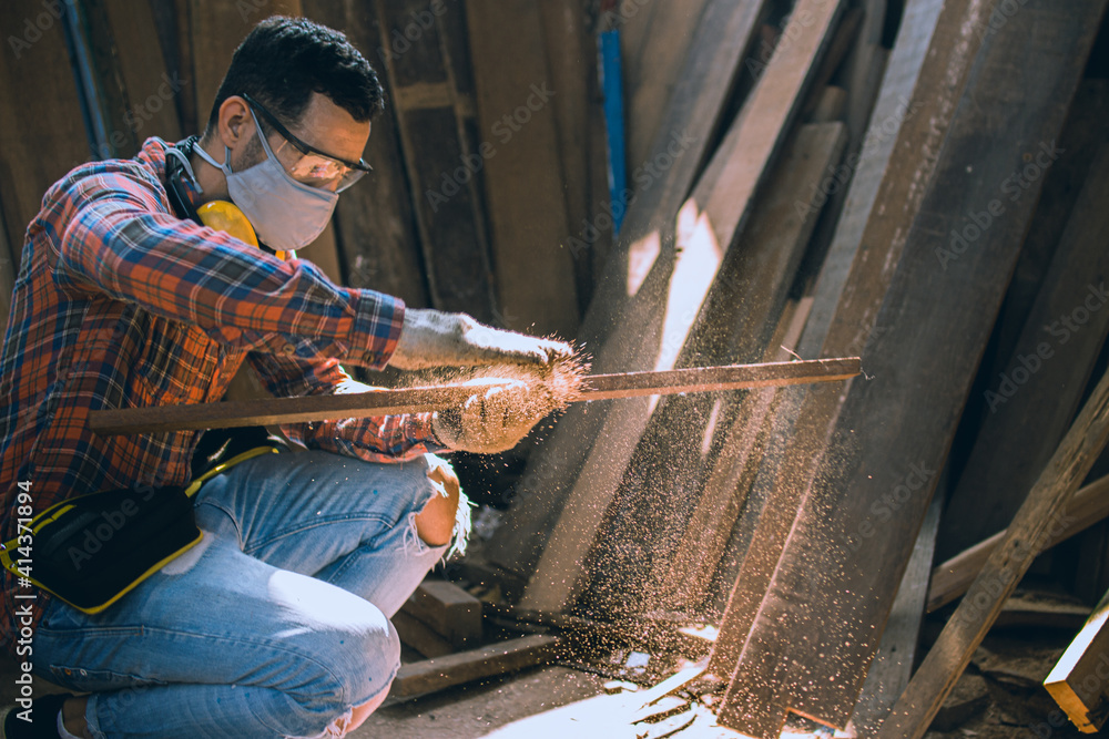 carpenter is working in a woodworking office.A white male carpenter is selecting the wood material and brushing off the sawdust. carpenter is working in a woodworking office.A white male carpenter is selecting the wood material and brushing off the sawdust.