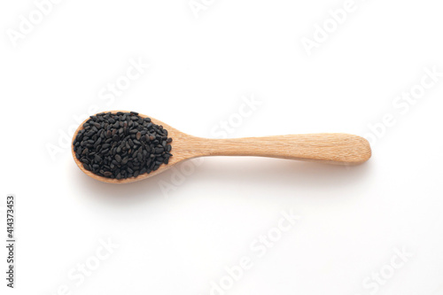 Black sesame in wooden spoon isolated on a white background, top view. photo
