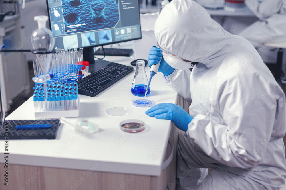 Focused lab technician pipetting solution into petri dish working on