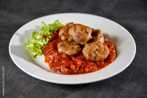 Homemade chicken meatballs in tomato sauce on dark stone or concrete table