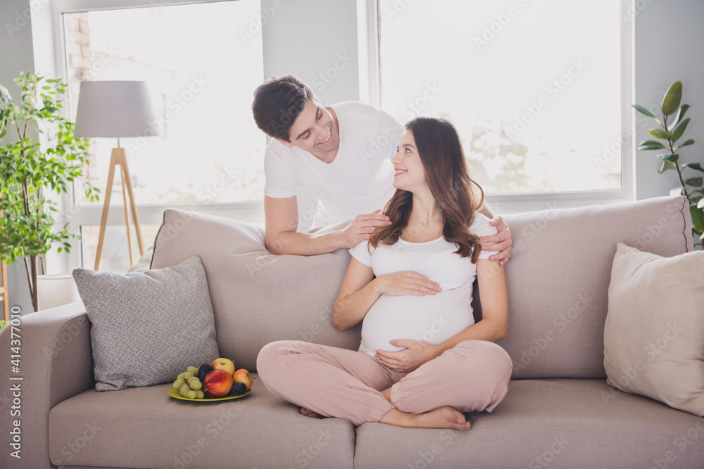 Photo of charming handsome couple expecting child sitting couch embracing belly inside indoors Photo of charming handsome couple expecting child sitting couch embracing belly inside indoors