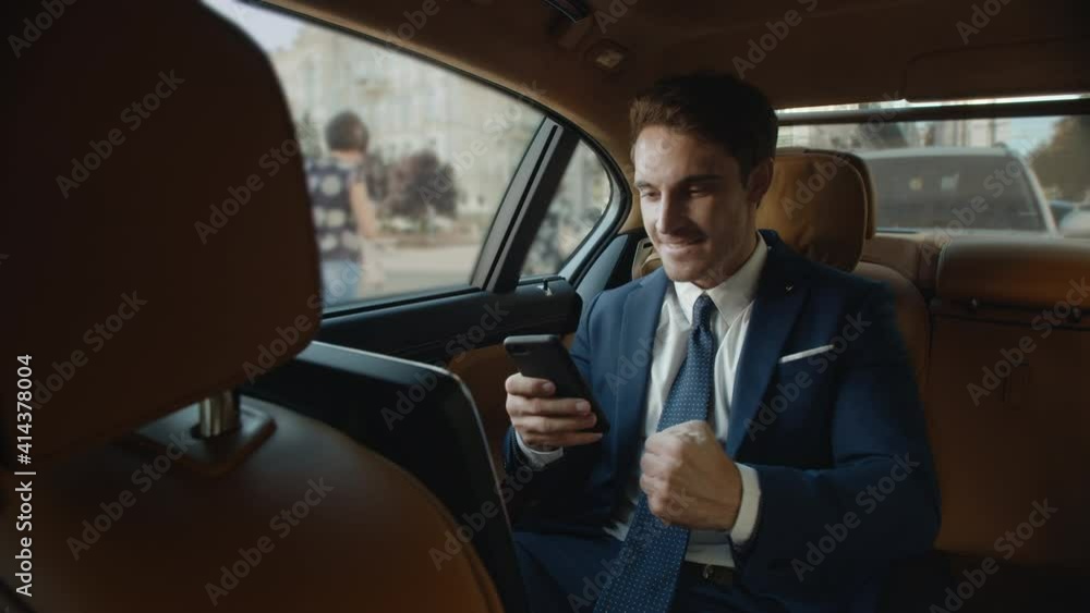 Surprised businessman getting good news on smartphone in interior of modern car. Surprised businessman getting good news on smartphone in interior of modern car.