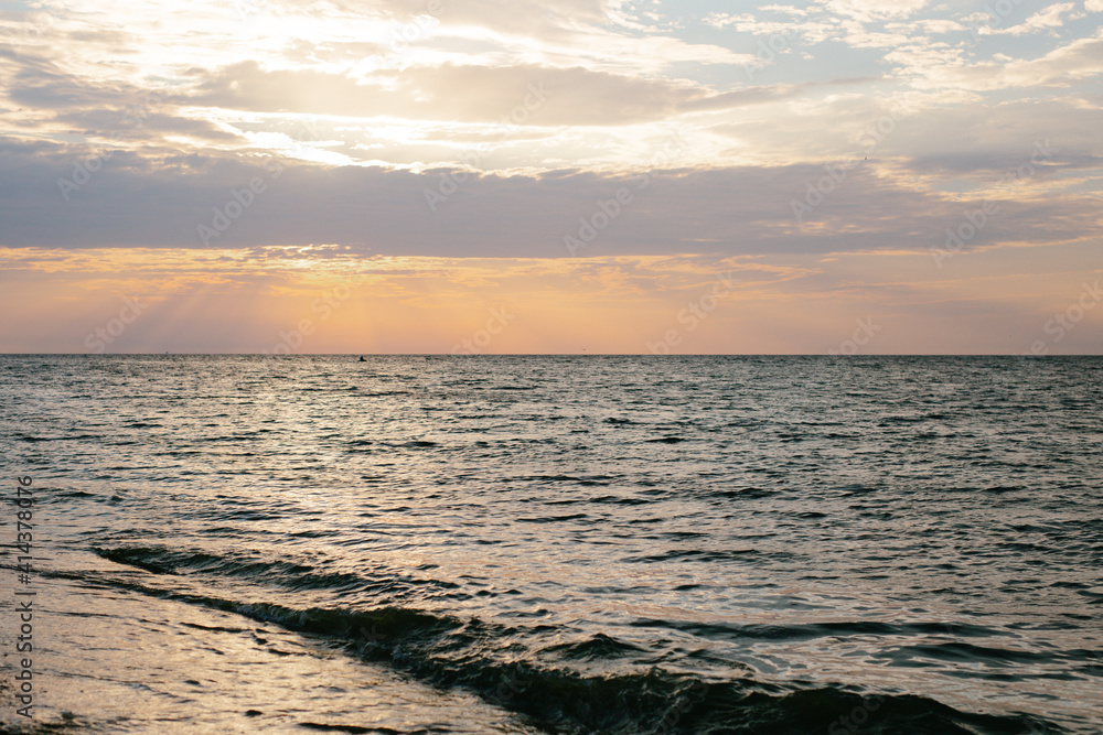 Sunset by the sea. Warm colors. There are no people. The photo is horizontal, color.